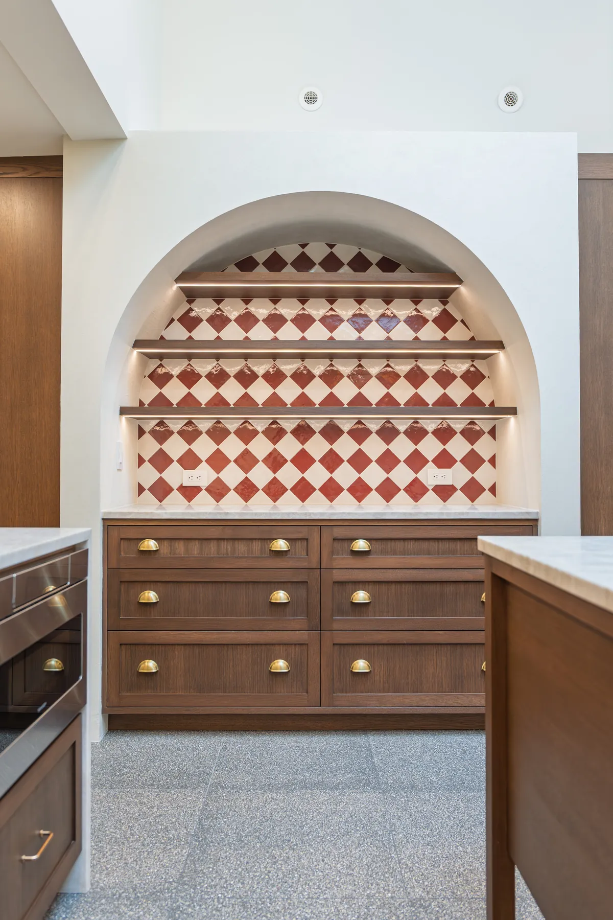 Arched niche with tiled backsplash and walnut cabinetry