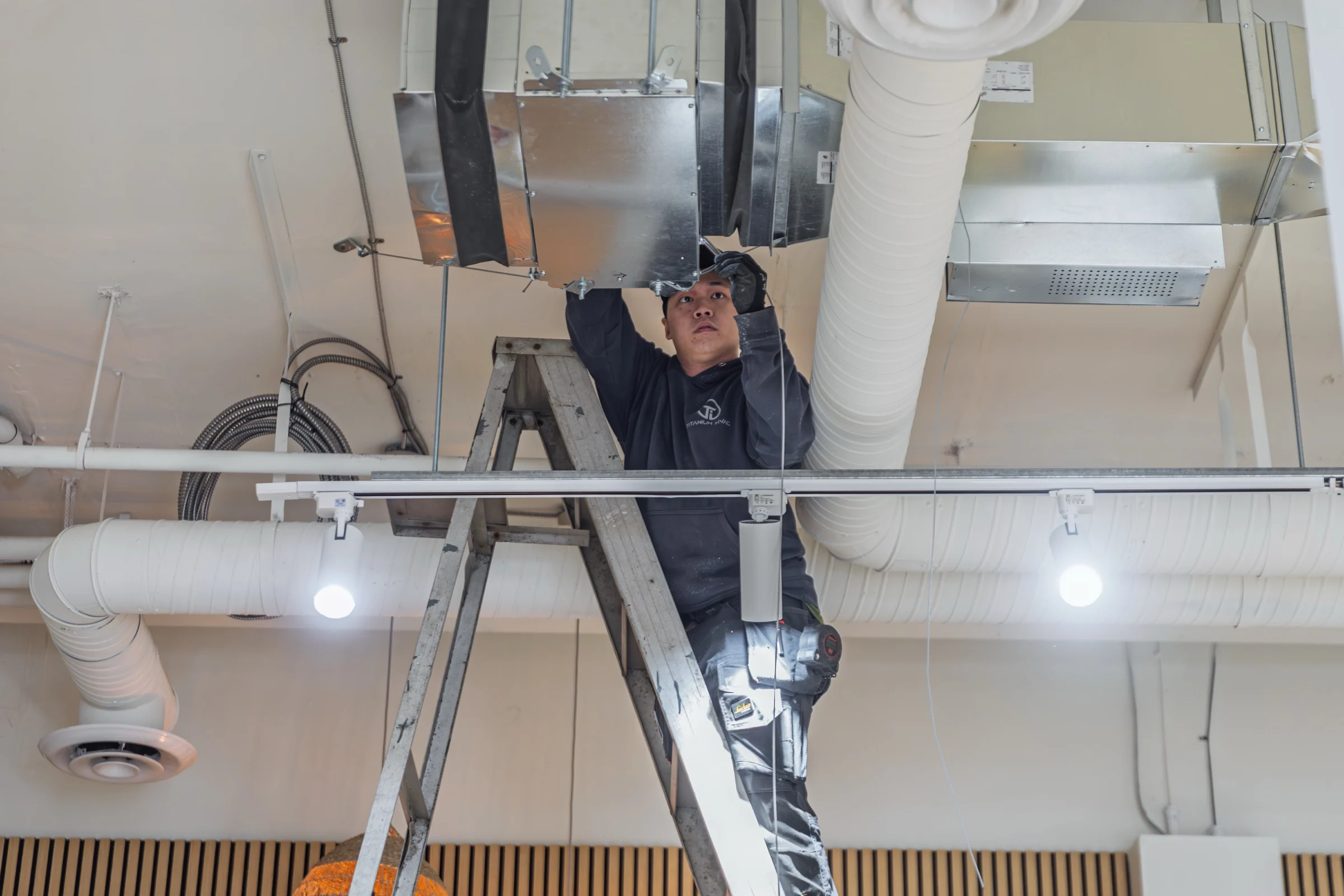 Titanium technician installing overhead ductwork